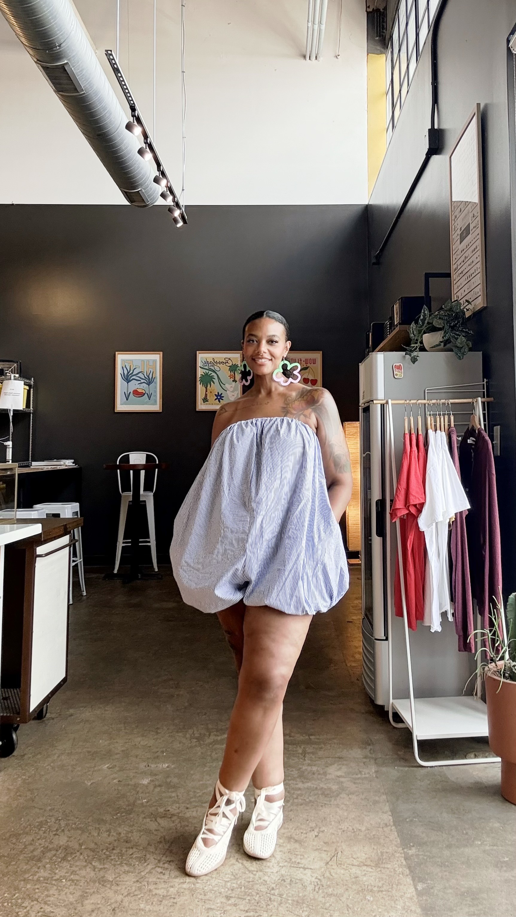 Aaronica B. Cole, sewing educator and pattern designer, standing in a studio wearing a striped bubble-hem romper